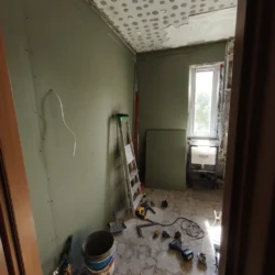 Zielone płyty na ścianach łazienki podczas zabudowy, z narzędziami na podłodze.