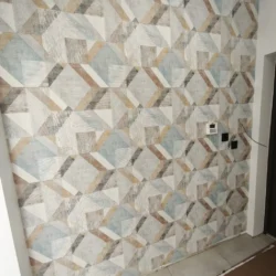 Tapeta w geometryczny wzór z szarych, beżowych i jasnoniebieskich figur wokół osprzętu elektrycznego