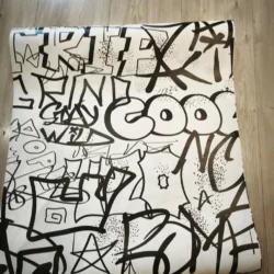 Rozwinięta tapeta z czarnymi napisami i rysunkami w stylu graffiti na jasnym tle